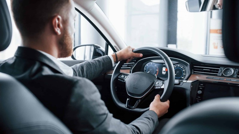 Modern businessman trying his new car in the automobile salon.